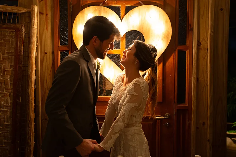Casal de noivos em frente a um coração iluminado